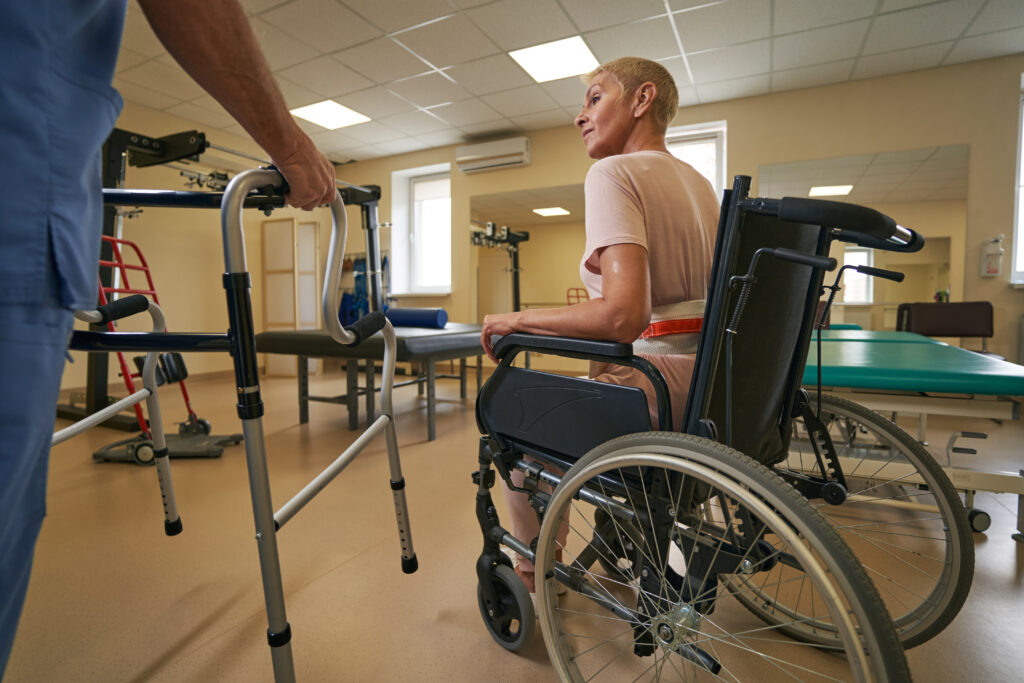 Healthcare professional helping stroke woman to use walker in clinic